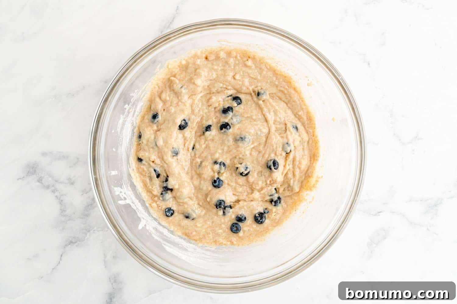 Fresh blueberries delicately folded into the muffin batter, showing an even distribution without being crushed.