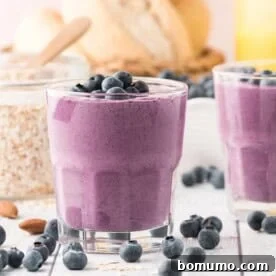 Blueberry smoothie in a short glass, topped with fresh blueberries.