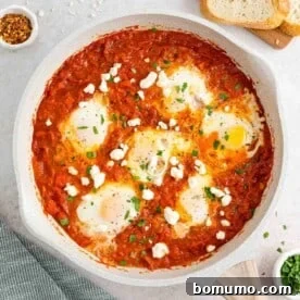 Shakshuka in a white skillet topped with feta cheese.
