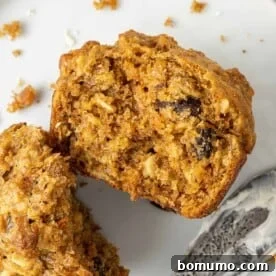 Carrot muffin split open to show texture and contents, including raisins and oats.