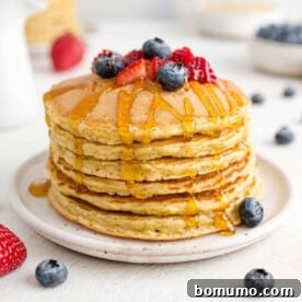Quinoa pancakes stacked with berries and syrup.