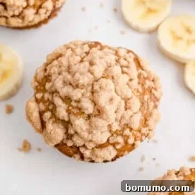 An appetizing overhead view of a golden brown whole wheat banana muffin, generously topped with a crumbly streusel.