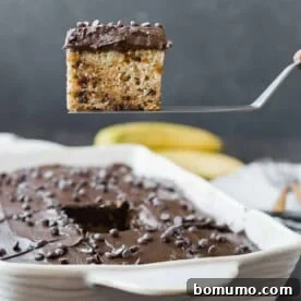 A tempting photo of banana chocolate chip cake with rich chocolate cream cheese frosting, being scooped directly from the pan.