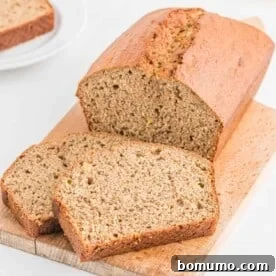 A perfectly baked loaf of whole wheat banana bread, partially sliced to reveal its moist texture.