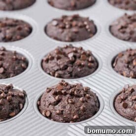 A muffin pan filled with wholesome triple chocolate banana muffins, each generously sprinkled with mini chocolate chips.