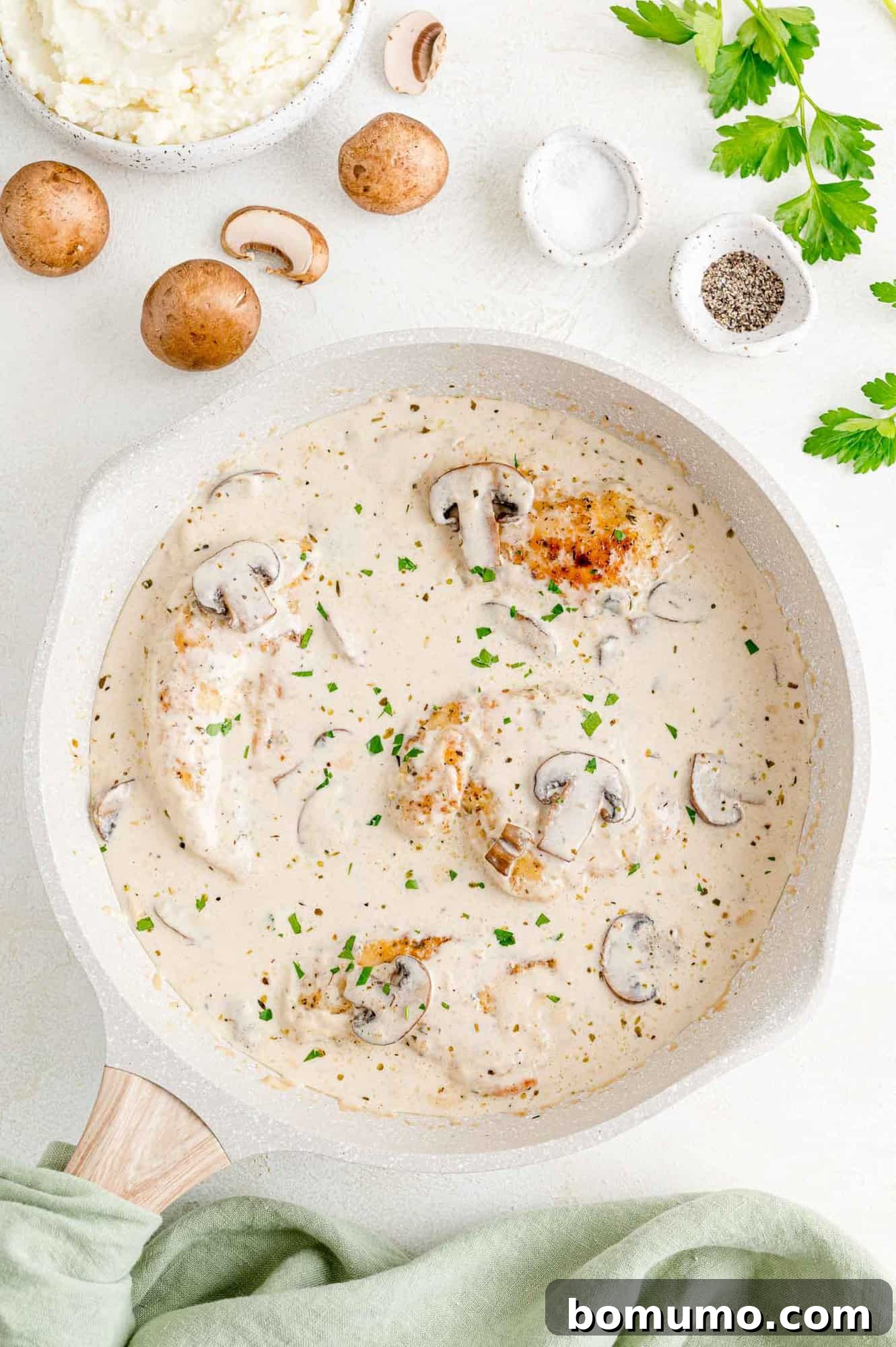 Pan-fried chicken cutlets immersed in a creamy Marsala sauce with mushrooms, glistening and ready to serve.