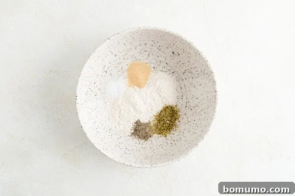 A bowl containing a mixture of flour and seasonings for dredging chicken.
