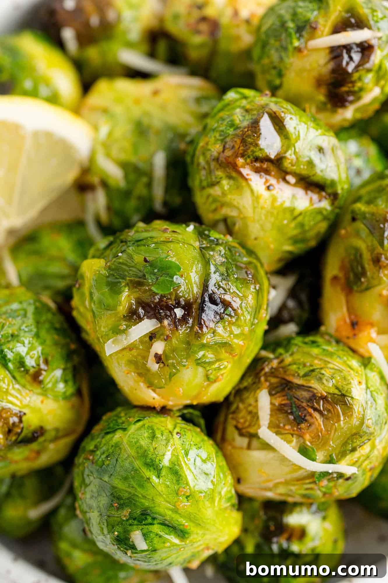 These are the best grilled Brussels sprouts! Cooked until golden and tossed in a combination of zesty lemon, parmesan, and fresh herbs. Close up of grilled Brussels sprouts tossed in lemon juice and grated parmesan.