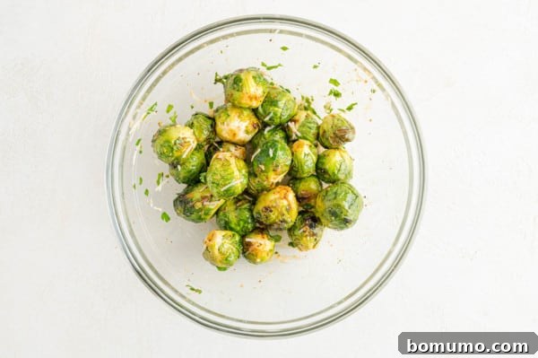 These are the best grilled Brussels sprouts! Cooked until golden and tossed in a combination of zesty lemon, parmesan, and fresh herbs. Grilled Brussels sprouts tossed in lemon juice and parmesan in a glass bowl
