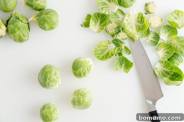 These are the best grilled Brussels sprouts! Cooked until golden and tossed in a combination of zesty lemon, parmesan, and fresh herbs. Trimmed and peeled Brussels sprouts on a countertop next to discarded leaves and a sharp knife.