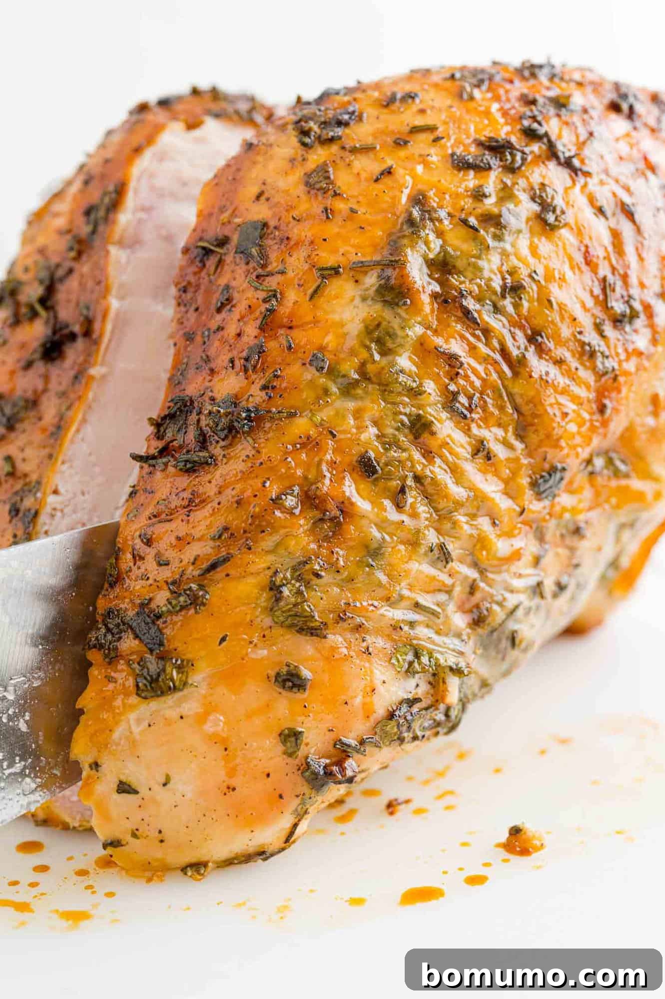 A chef's knife carefully slicing through the tender, juicy meat of a freshly roasted turkey breast, revealing its perfectly cooked interior.