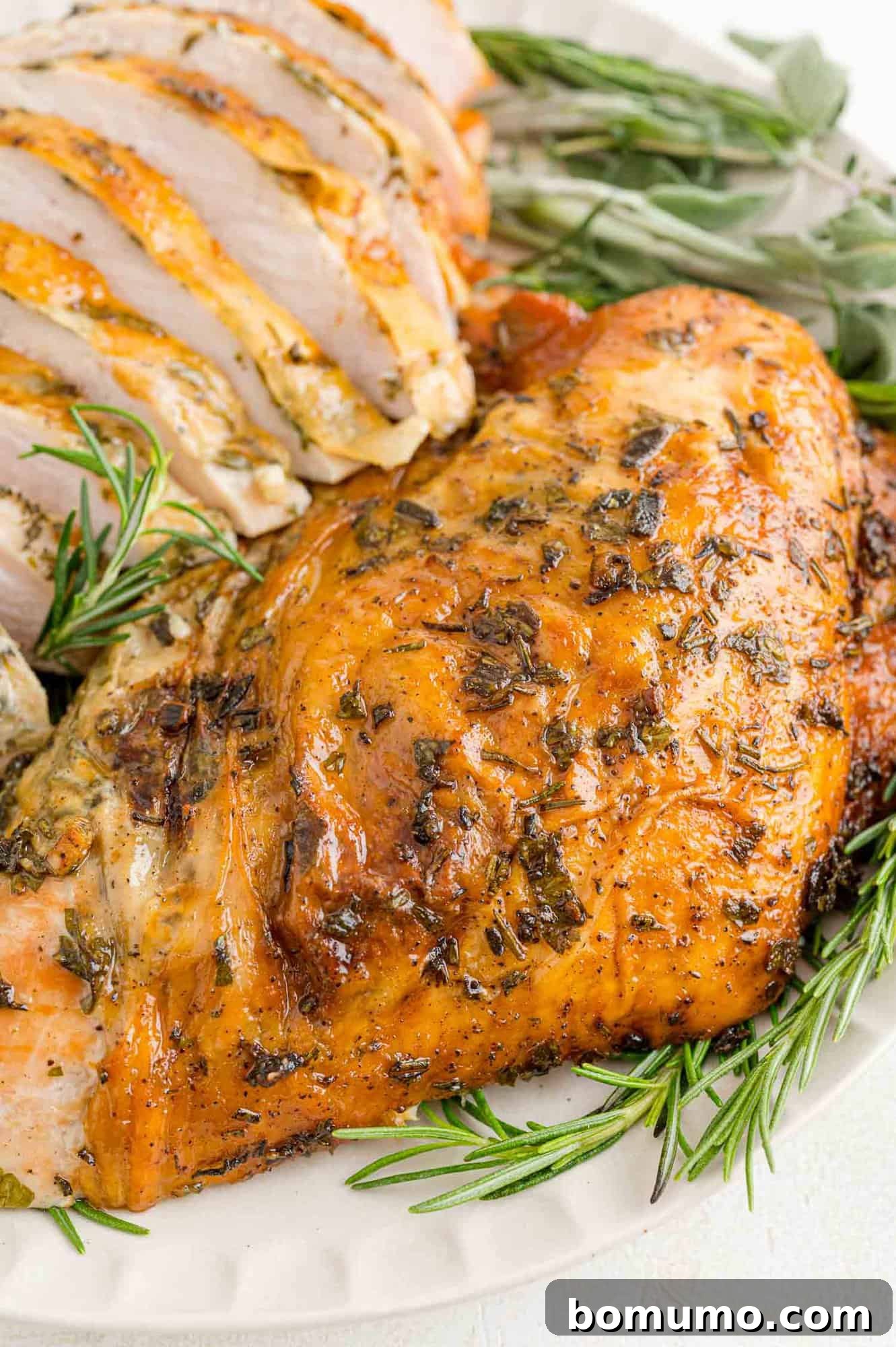 A beautifully browned herb-rubbed roasted turkey breast resting on a platter, garnished with sprigs of fresh rosemary and thyme, ready for carving.