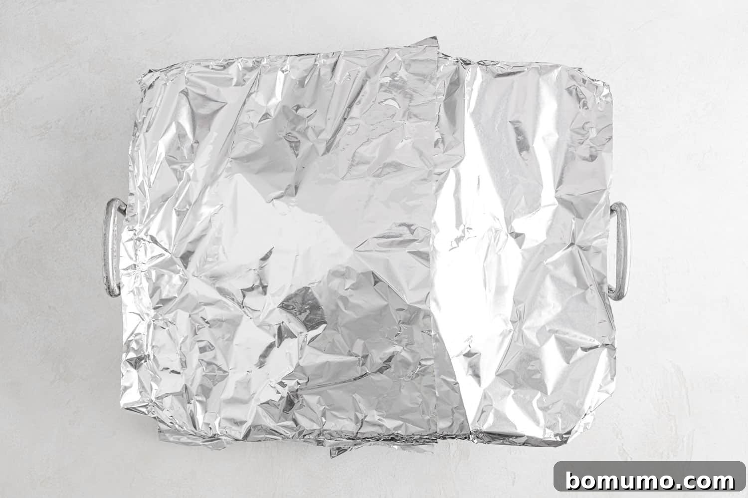 A roasted turkey breast partially covered with a loose sheet of aluminum foil, indicating it's preventing over-browning while cooking.