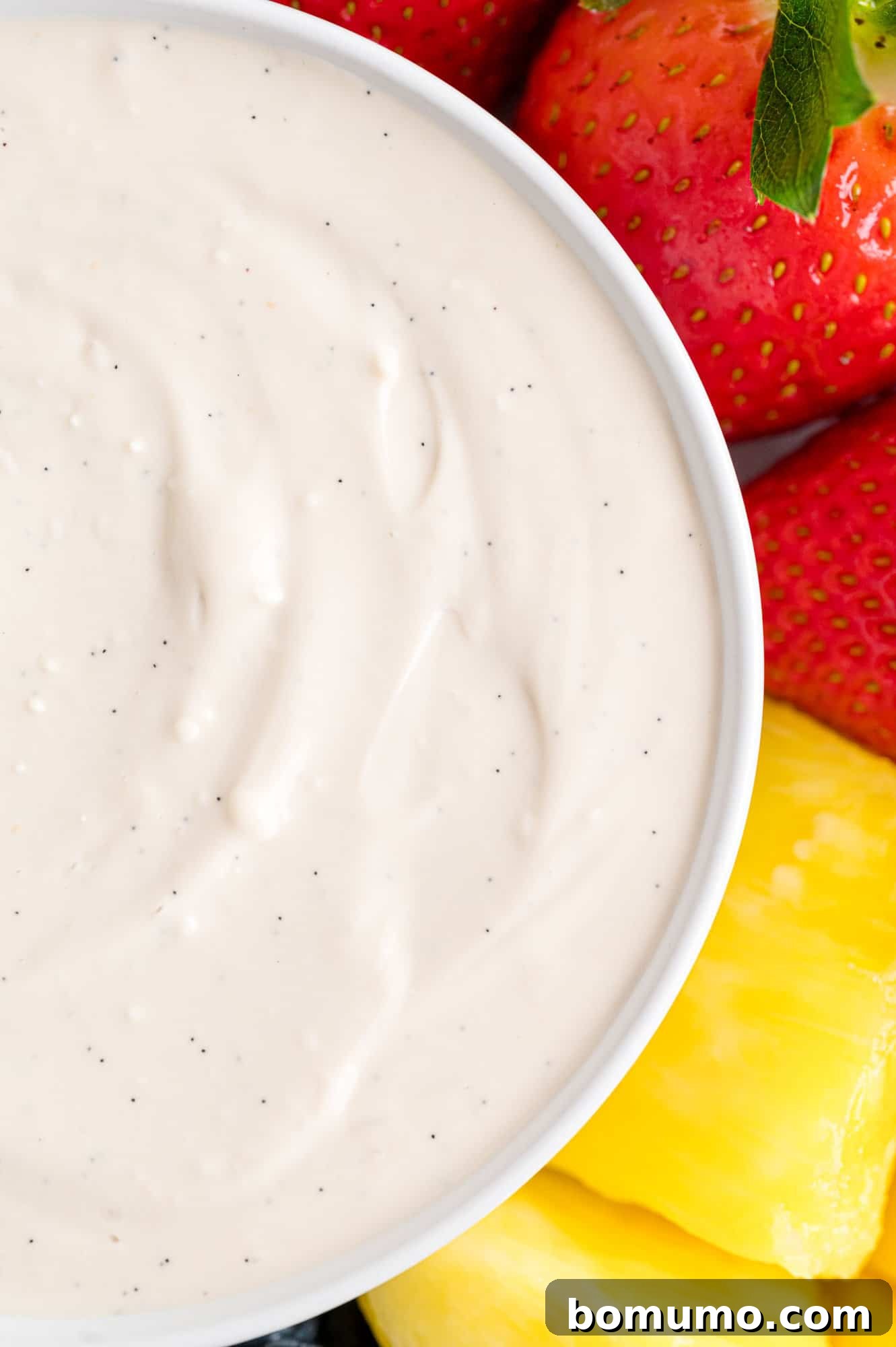 Close up of a bowl of cream cheese fruit dip next to assorted fruit.