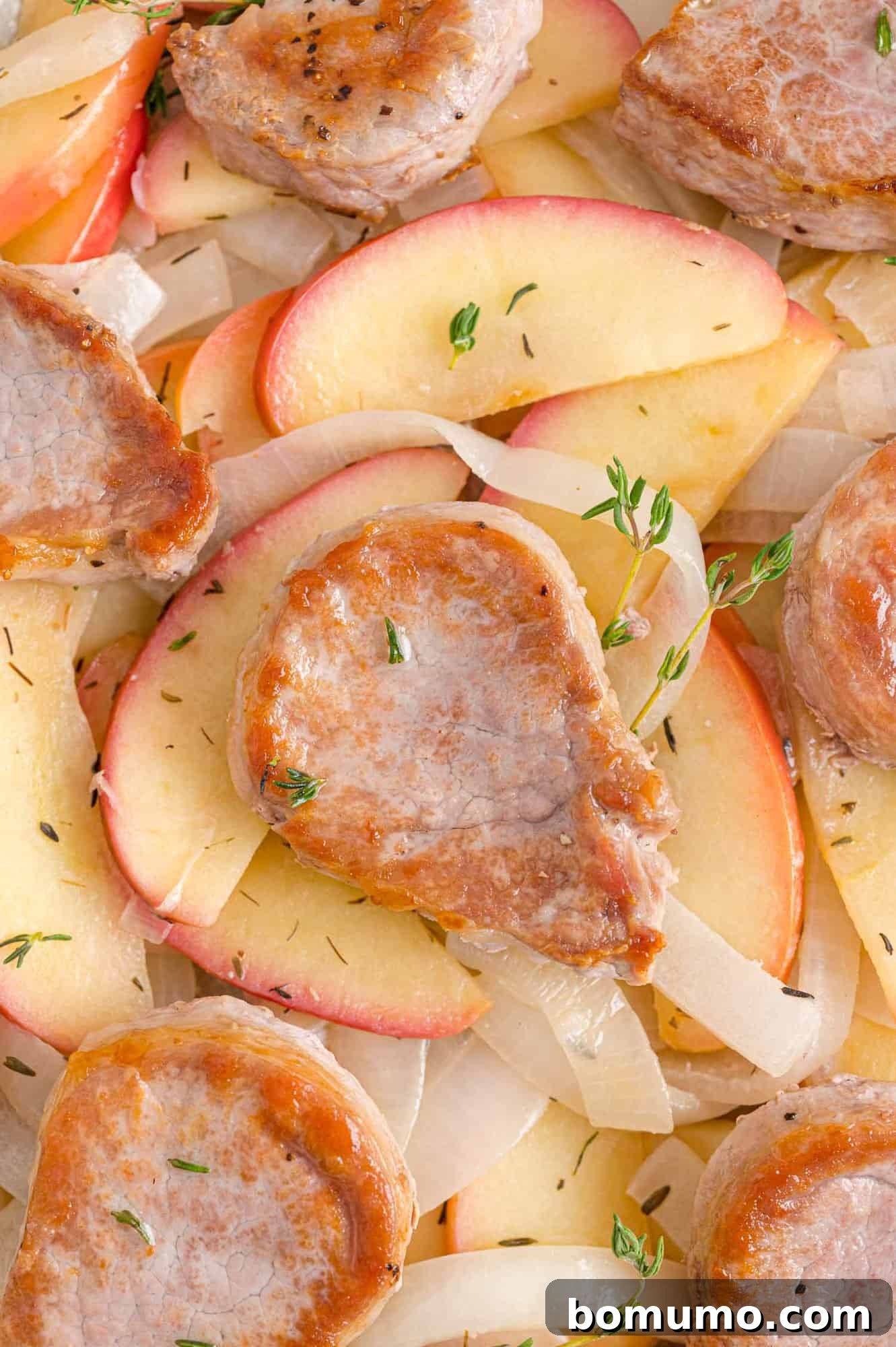 Succulent pork tenderloin slices arranged with tender, caramelized apples and onions, garnished with fresh thyme. A perfect autumn meal.