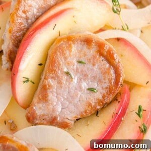 Pork tenderloin and apples garnished with fresh thyme, presented beautifully on a plate.