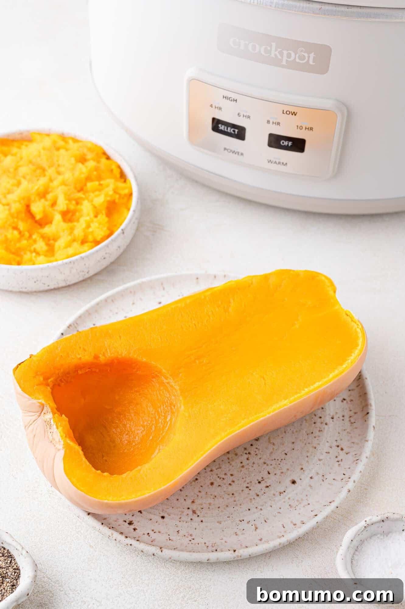 Crockpot butternut squash, half still in peel, half in bowl, showcasing its tender texture.
