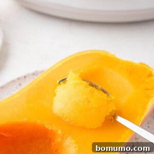 Crockpot butternut squash being scooped from the peel of squash.
