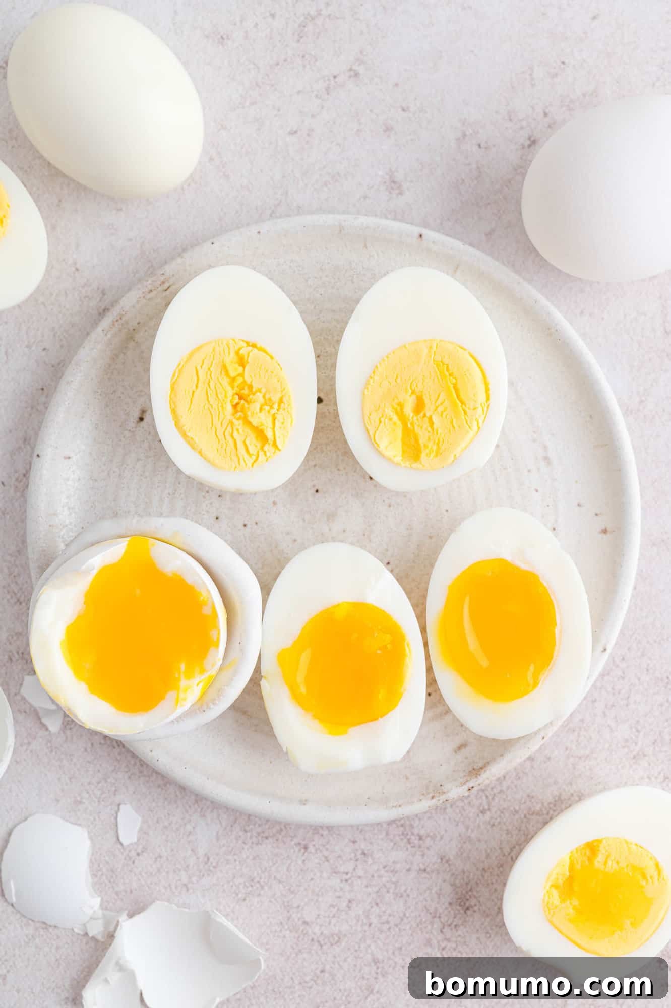 A beautifully arranged plate featuring air fryer boiled eggs, some expertly sliced in half to reveal varying degrees of yolk doneness – from soft and runny to firm and fully cooked. A perfect representation of healthy, versatile egg preparation.