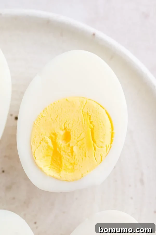 A close-up of one half of a perfectly hard-boiled egg on a plate, showcasing a firm, fully cooked yolk – the consistent result of 15 minutes of air frying.