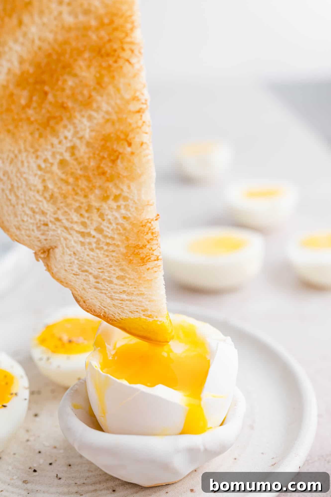 The corner of a crisp piece of golden toast delicately dipped into the rich, runny yolk of a perfectly soft-boiled egg, presented beautifully on a white plate. A classic and comforting breakfast delight.