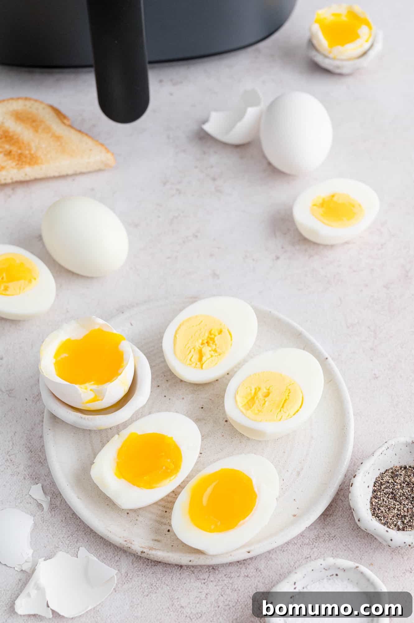A vibrant breakfast spread featuring air fryer boiled eggs, halved to showcase their perfectly cooked yolks, alongside fresh toast and various savory seasonings. An inviting and healthy meal option.