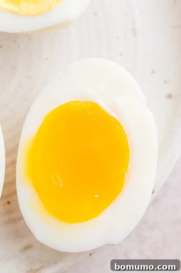 A close-up shot of one half of a jammy-centered boiled egg on a plate, beautifully displaying its creamy and slightly set yolk, achieved after 12 minutes in the air fryer.