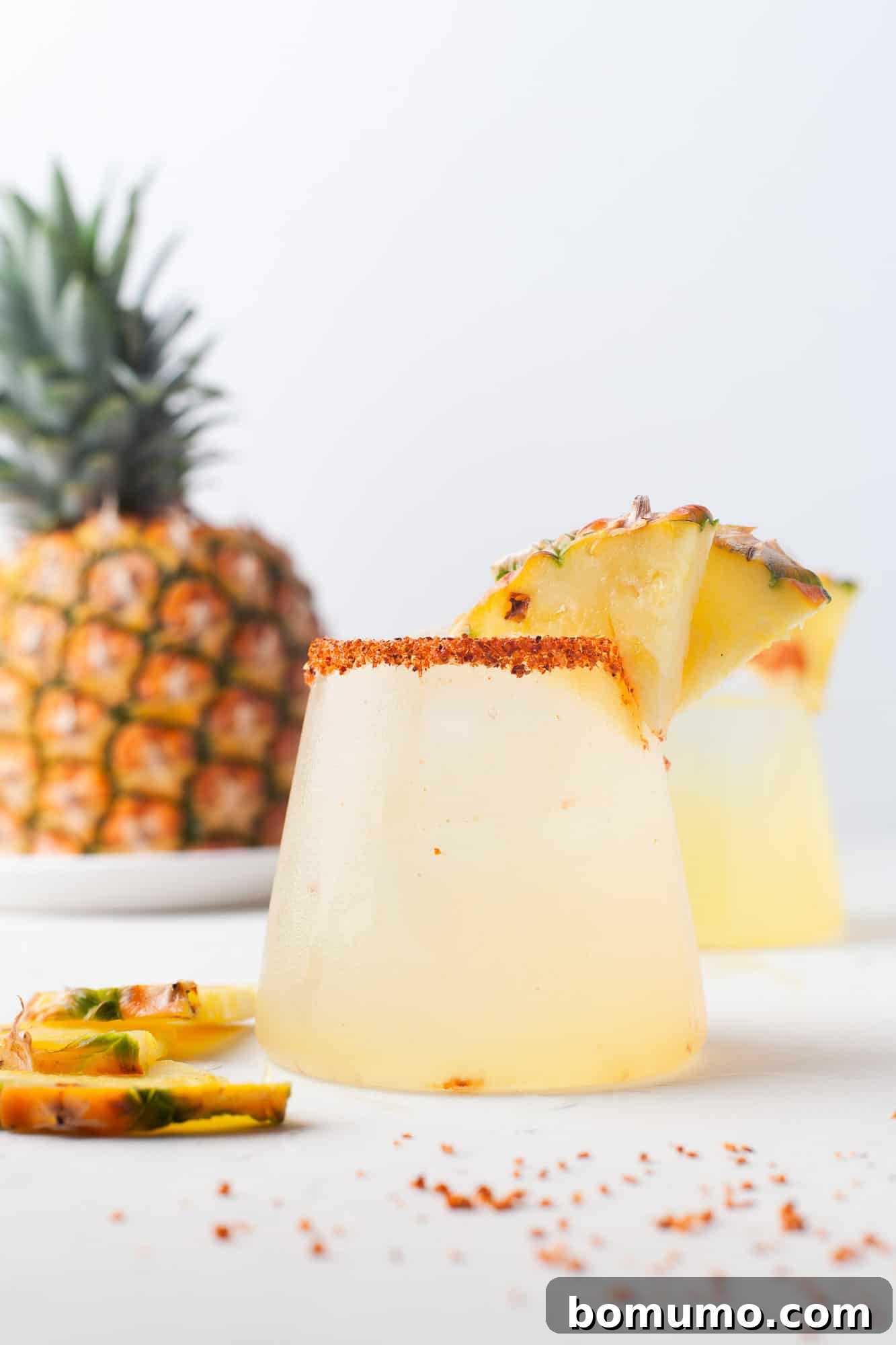 A refreshing pineapple margarita with a fresh pineapple in the background, showcasing its vibrant color and inviting presentation.