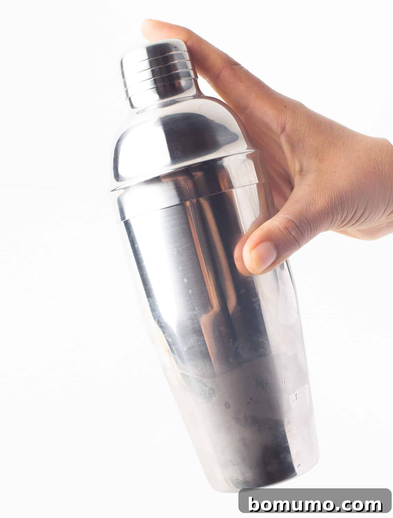 A cocktail shaker being vigorously shaken, indicating the mixing and chilling process for the pineapple margarita.