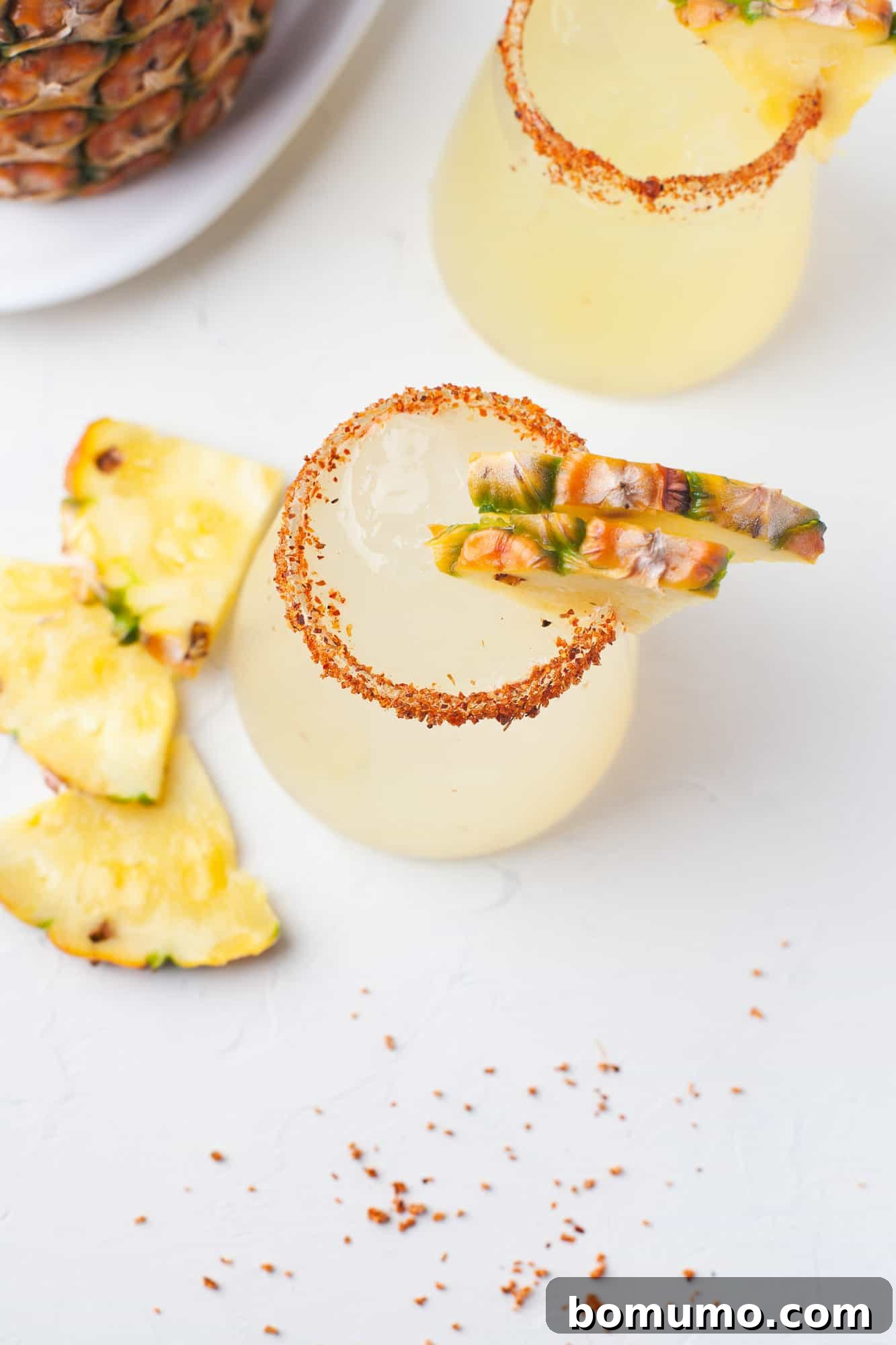 A perfectly crafted pineapple margarita with a chili-spiced rim, presented from an overhead view to highlight its inviting colors and texture.