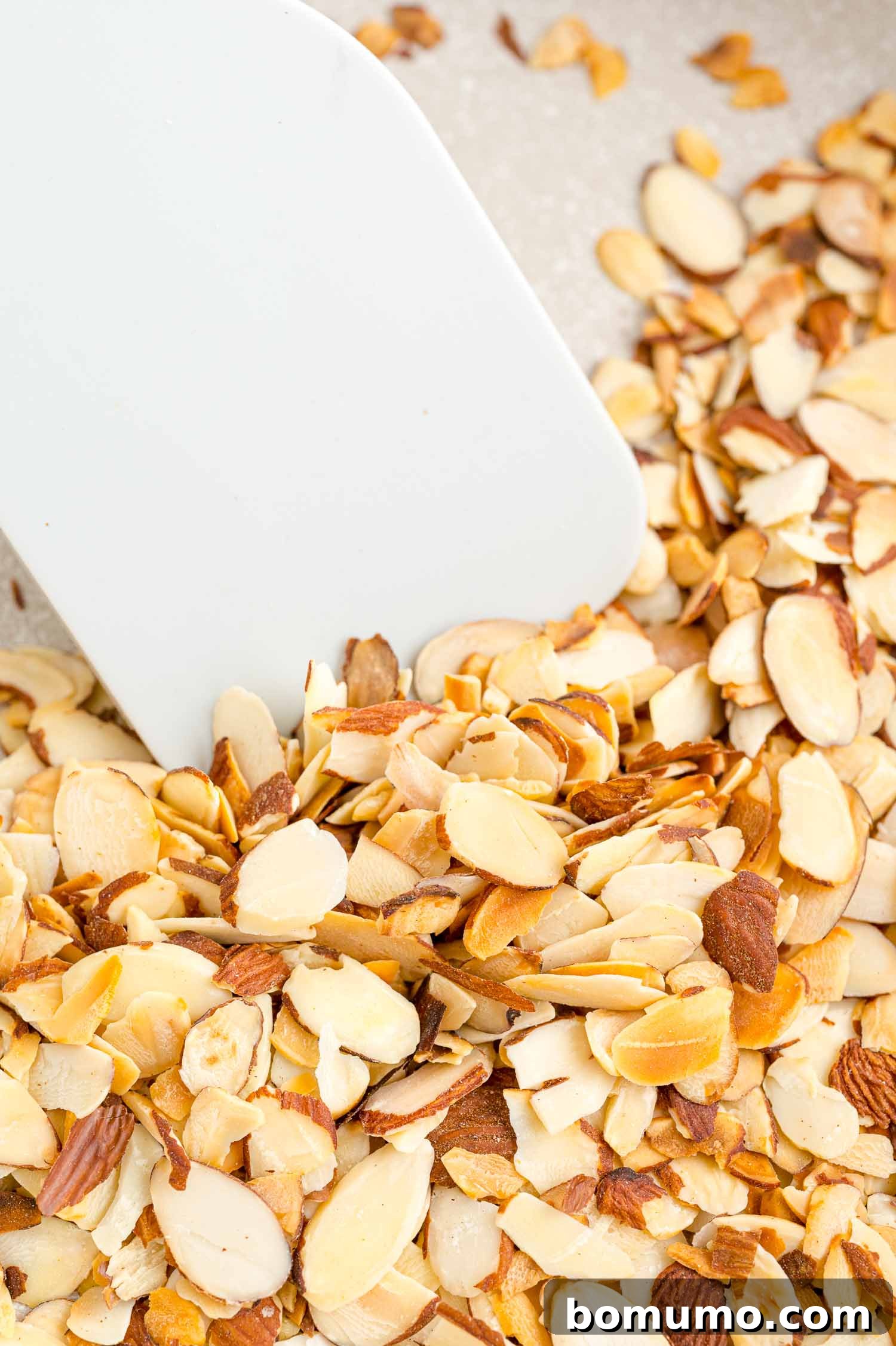 Toasting almonds is a great way to bring out their crunch and flavor. Learn how to toast almonds in the oven, microwave, and on the stovetop! Close up of a spatula stirring almonds as they toast in a skillet.