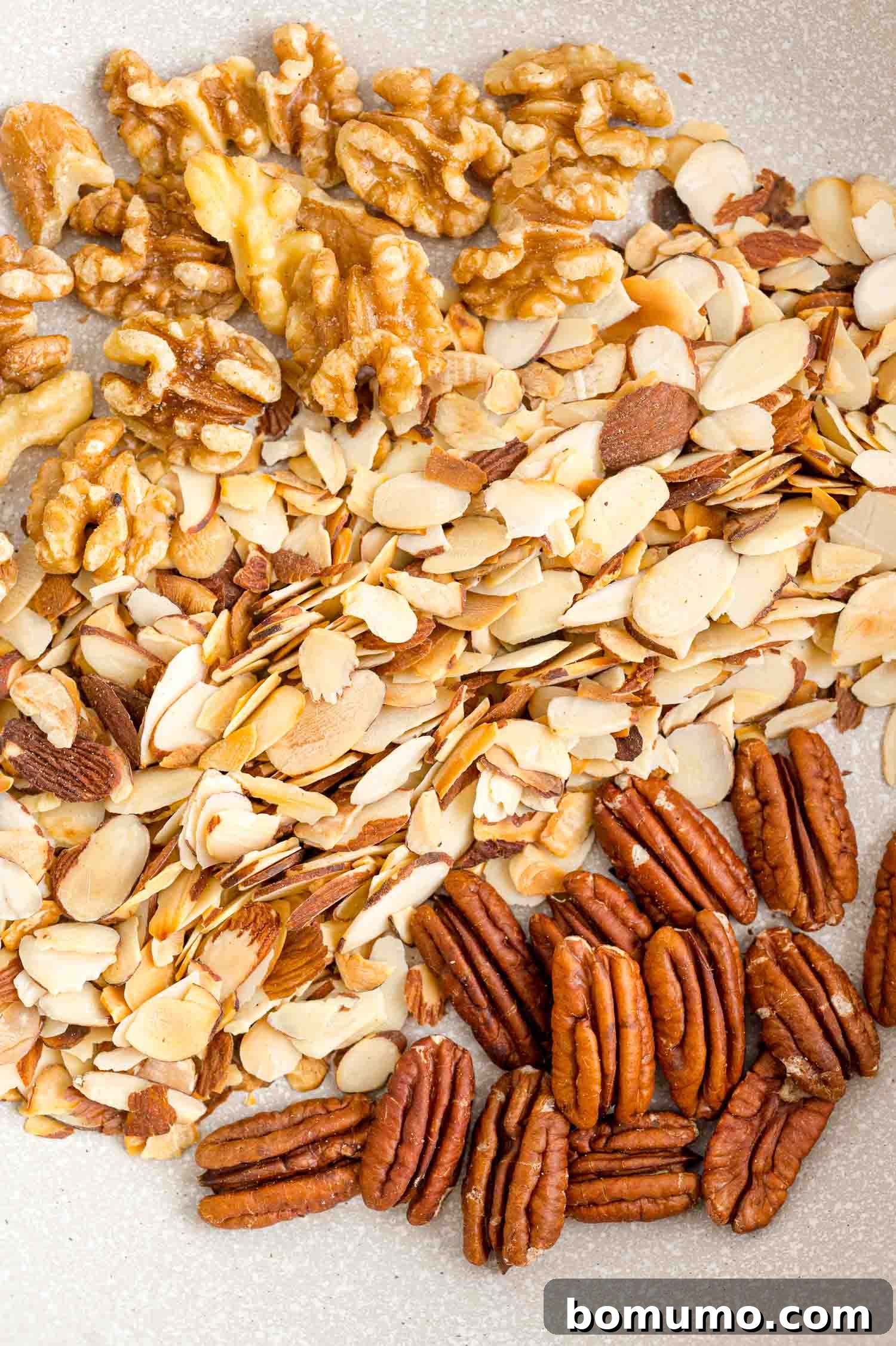 Toasting almonds is a great way to bring out their crunch and flavor. Learn how to toast almonds in the oven, microwave, and on the stovetop! Toasted almonds, walnuts, and pecans in a bowl.