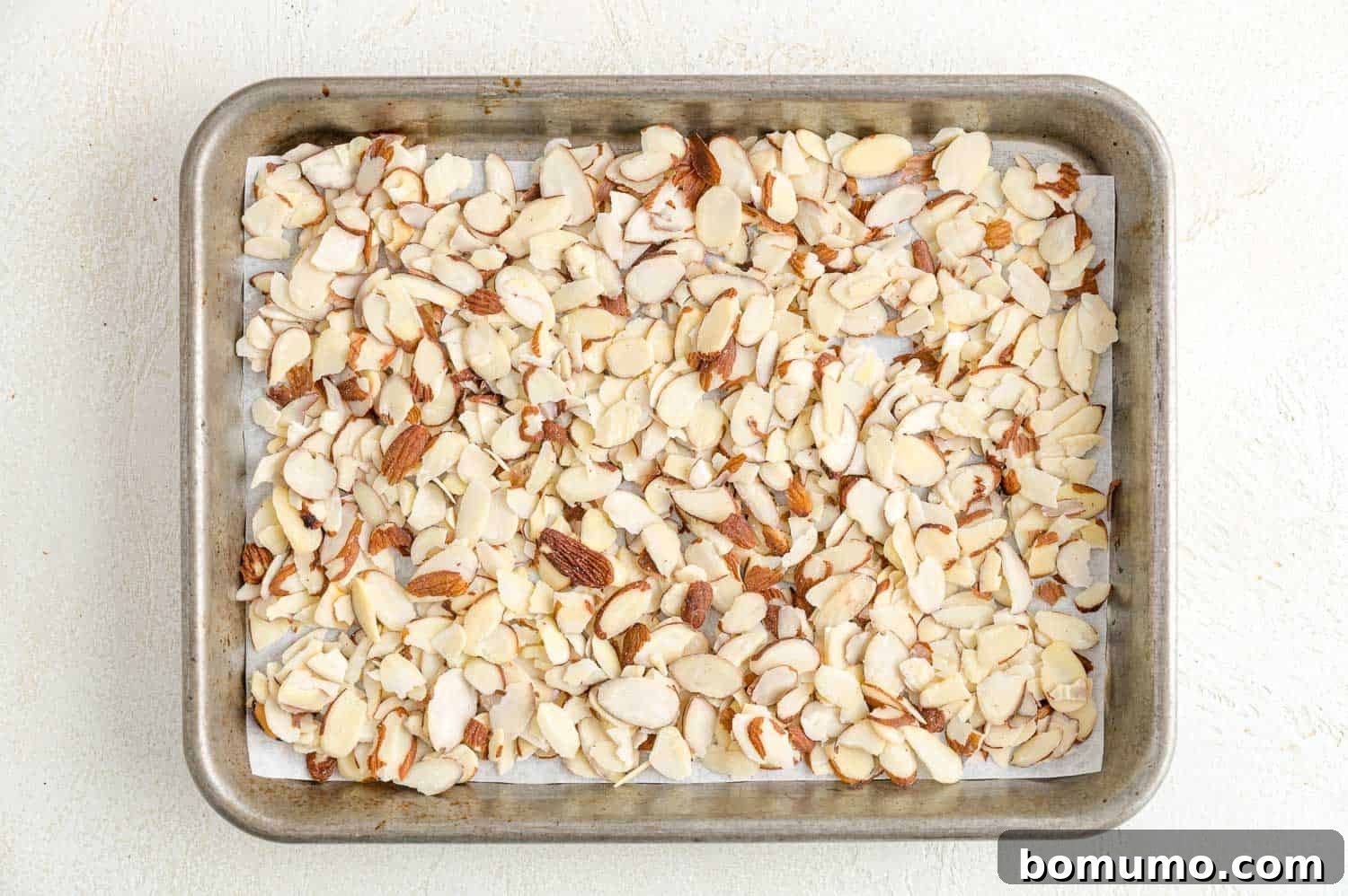 Toasting almonds is a great way to bring out their crunch and flavor. Learn how to toast almonds in the oven, microwave, and on the stovetop! Sliced almonds spread into an even layer on a parchment-lined baking sheet.