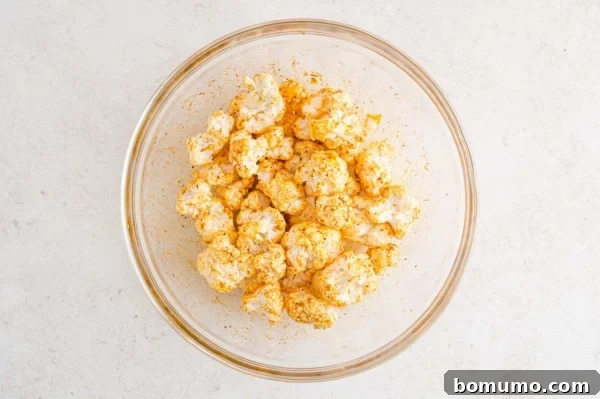 Seasoned cauliflower florets in a glass bowl.