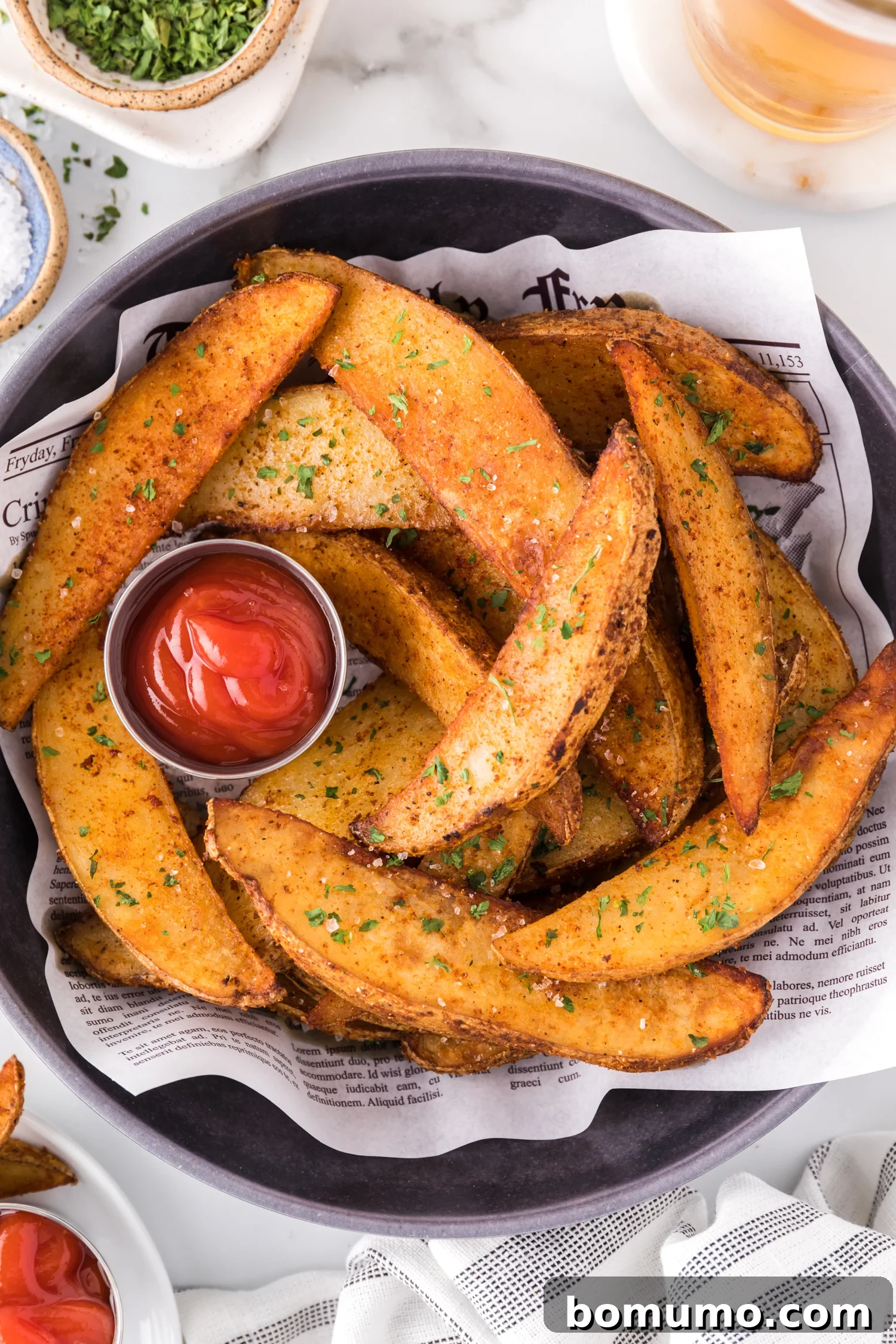 Golden brown air fryer potato wedges served in a basket with a side of ketchup.