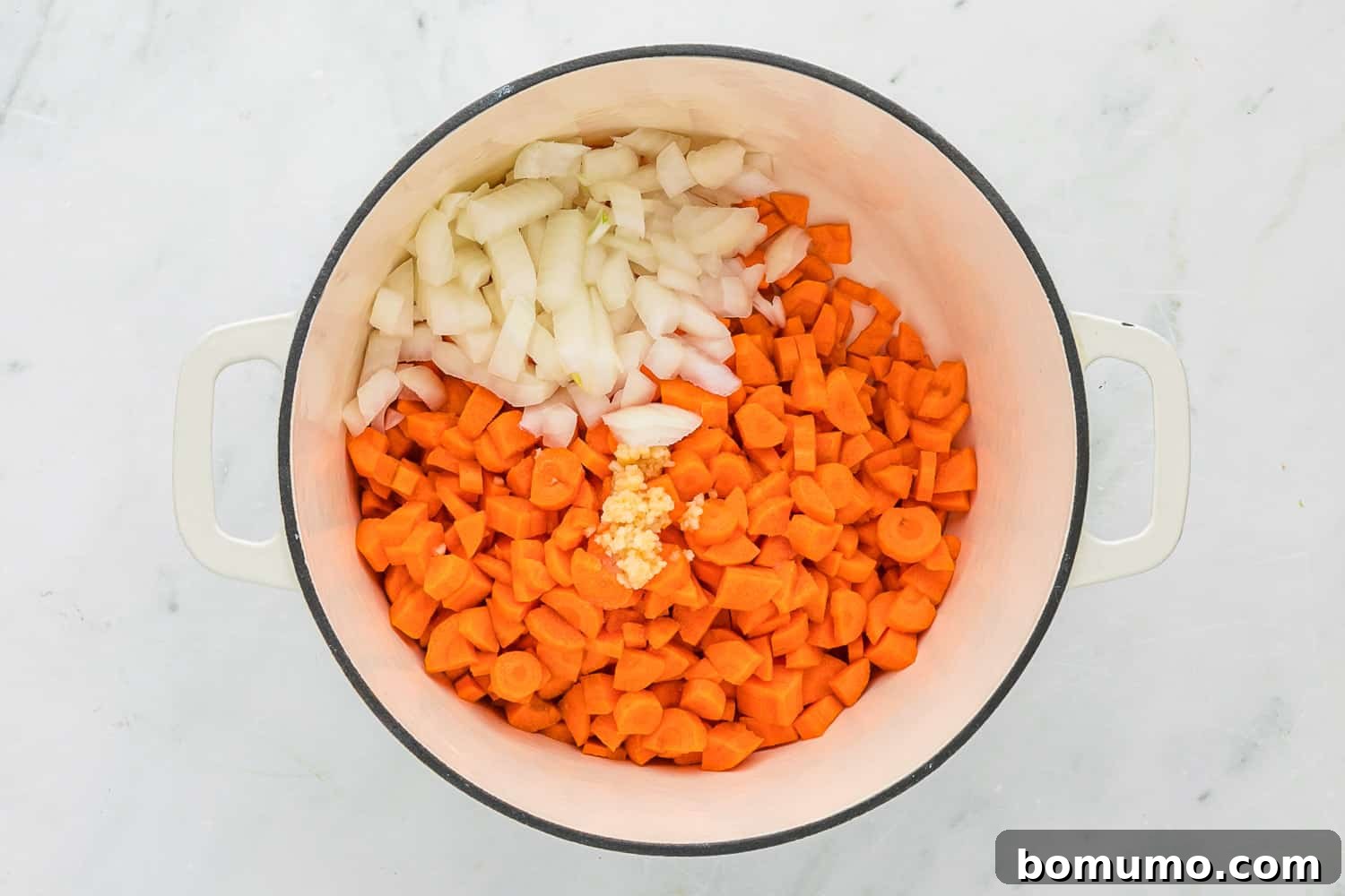 Chopped carrots and onions gently sautéing in a large soup pot.