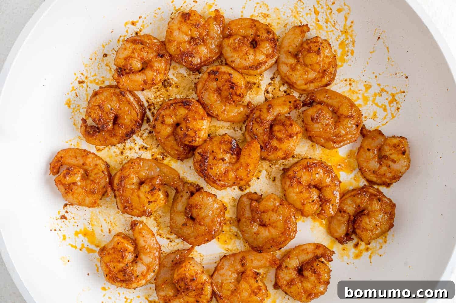 Marinated shrimp sizzling in a hot skillet, cooking to perfection.