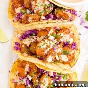 Three shrimp tacos with creamy drizzle and cotija cheese.
