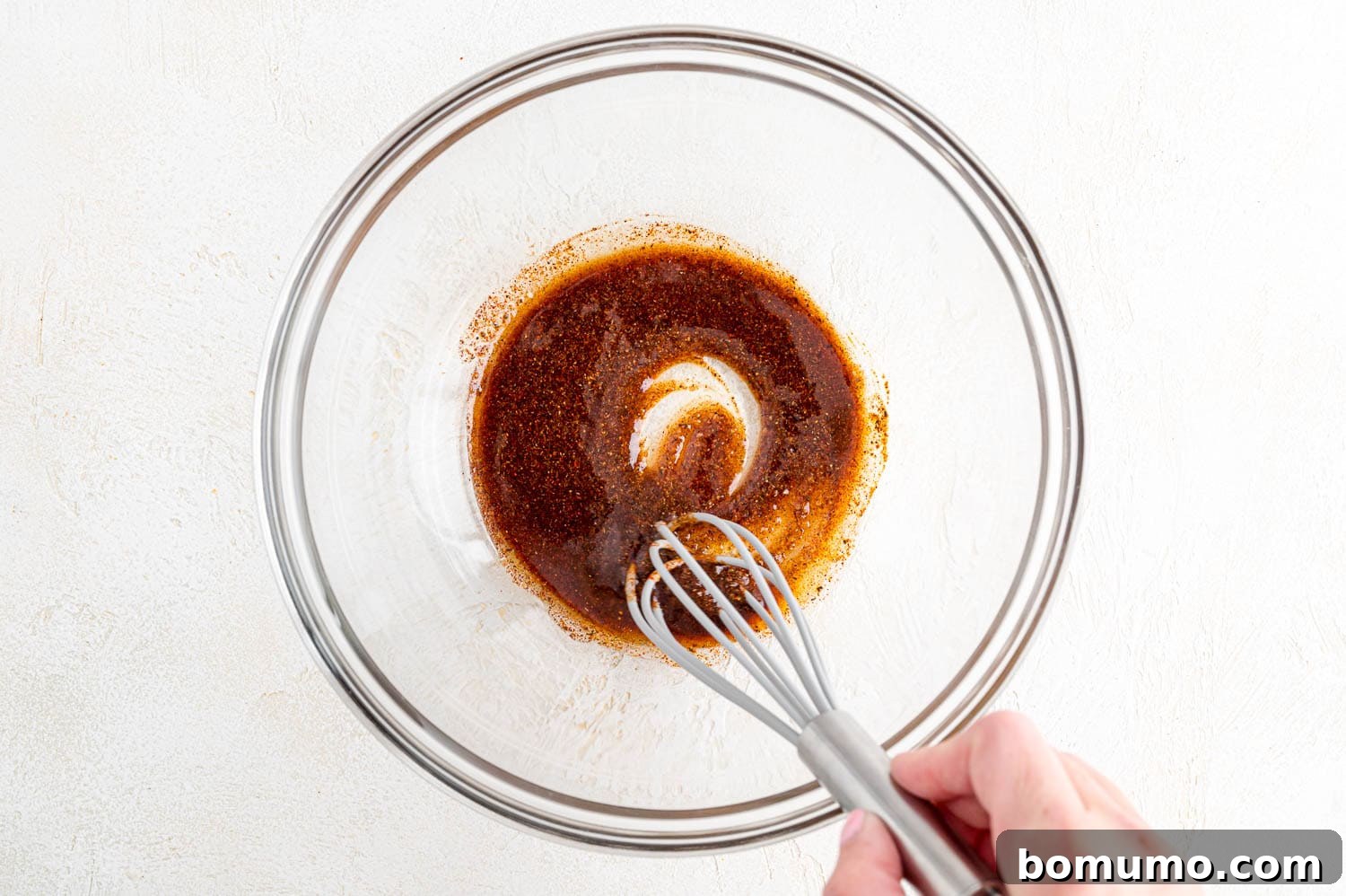 The shrimp marinade ingredients, including olive oil and spices, expertly mixed in a bowl.