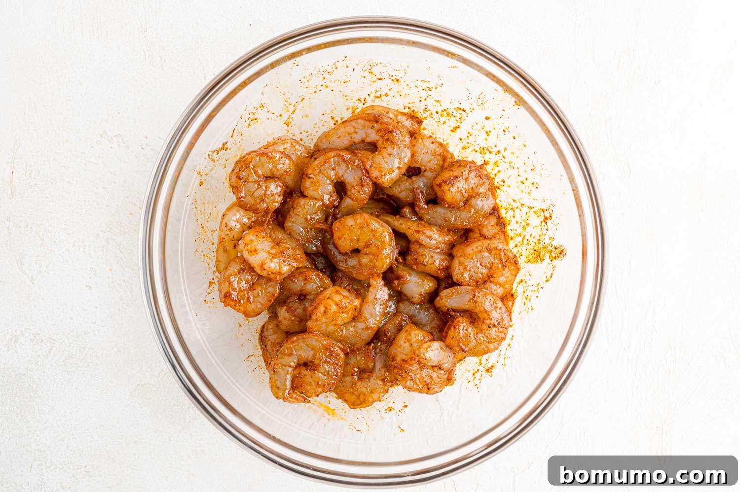 Shrimp perfectly coated in the flavorful marinade, ready for its brief resting period.