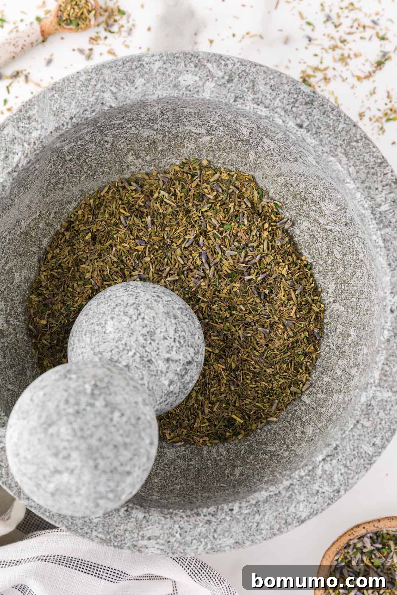 Dried herbs being gently ground in a traditional mortar and pestle, creating a fine, aromatic powder.