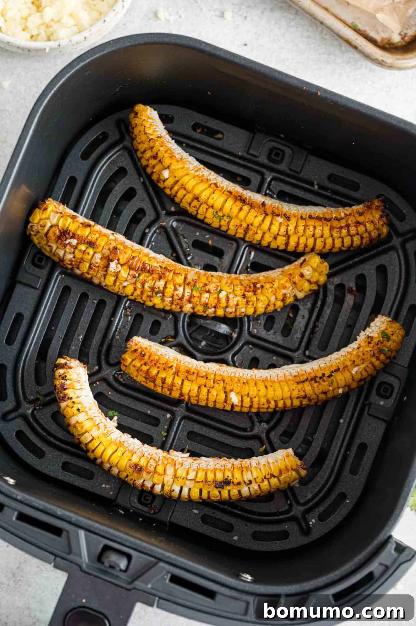 Seasoned corn ribs cooking in a single layer within an air fryer basket.