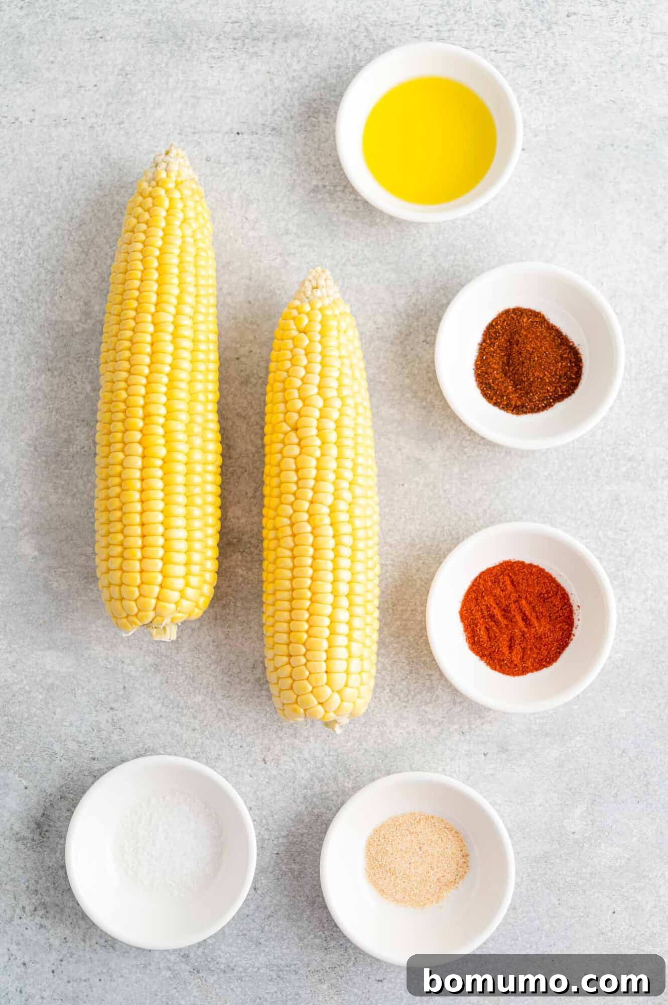 Ingredients for roasted corn ribs, including fresh corn, olive oil, and a selection of spices.
