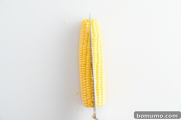 Corn halves being further cut into quarters, showing the technique to create corn ribs.