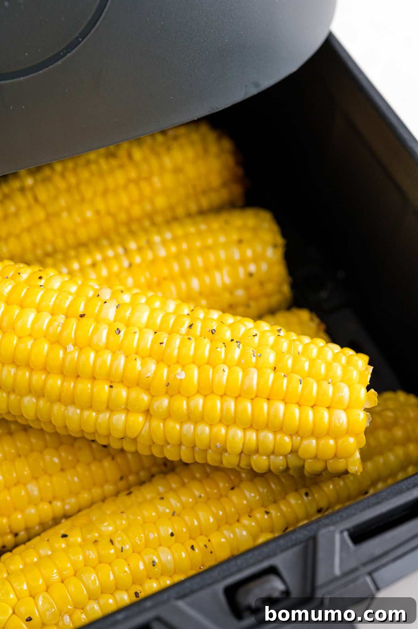Air fryer corn on the cob inside the open air fryer basket, showcasing a perfectly cooked batch.