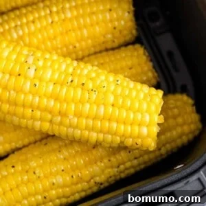 Air fryer corn on the cob in the air fryer basket, showing a perfect golden roast.
