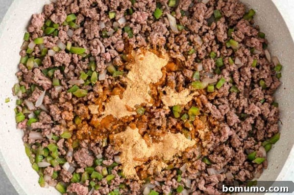 Taco seasoning added to browned ground beef in a skillet.