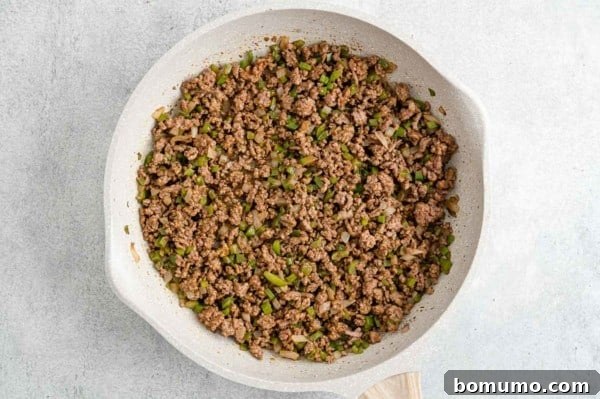 Seasoned ground beef in a white skillet.