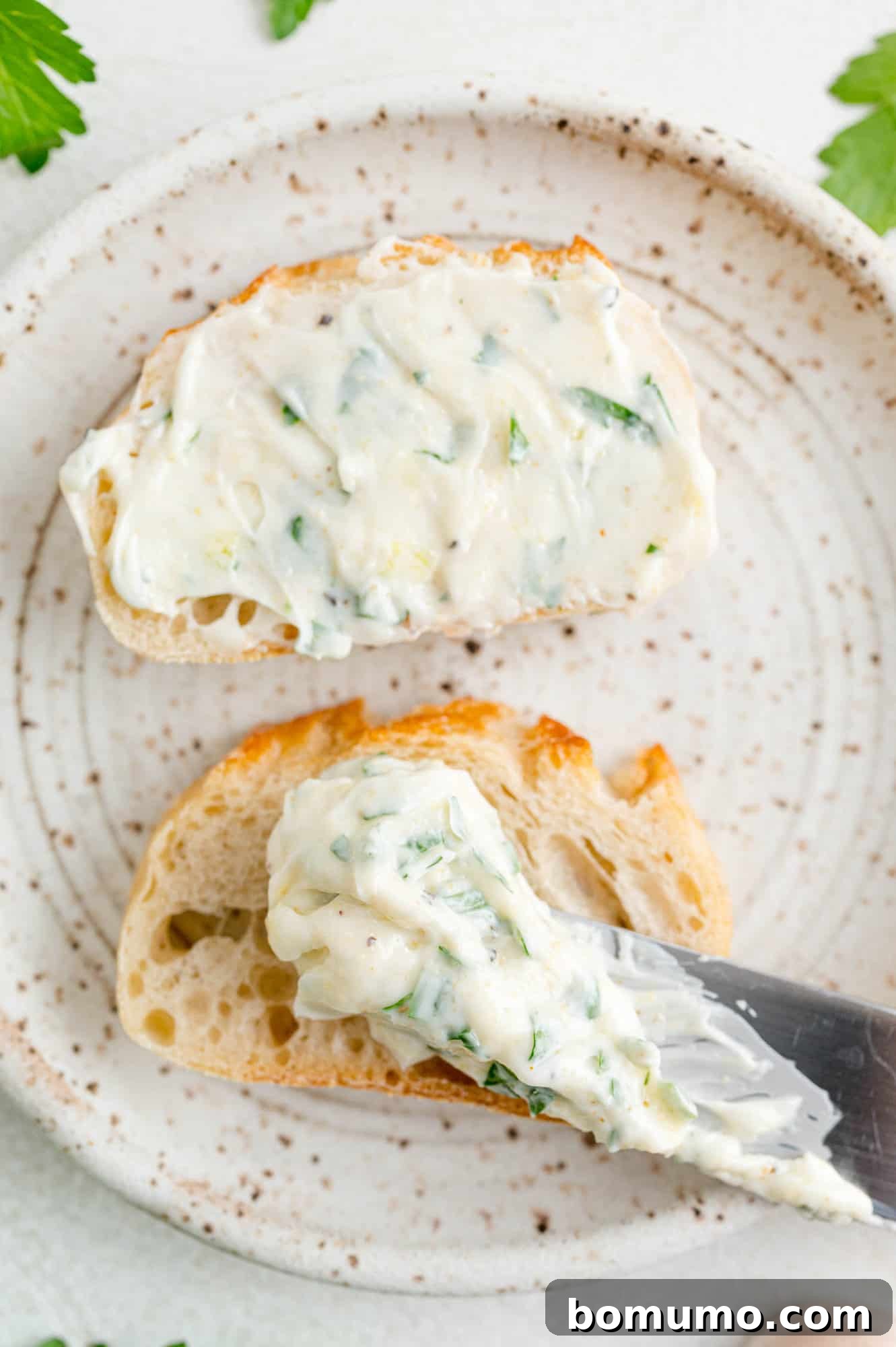 Freshly made garlic butter being spread on a small piece of toasted bread, showcasing its creamy texture.