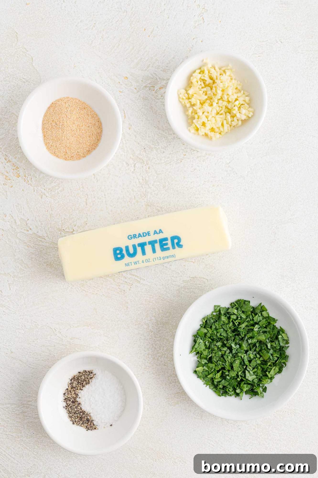 Arrangement of fresh garlic, parsley, and butter sticks, showcasing the core ingredients for the recipe.